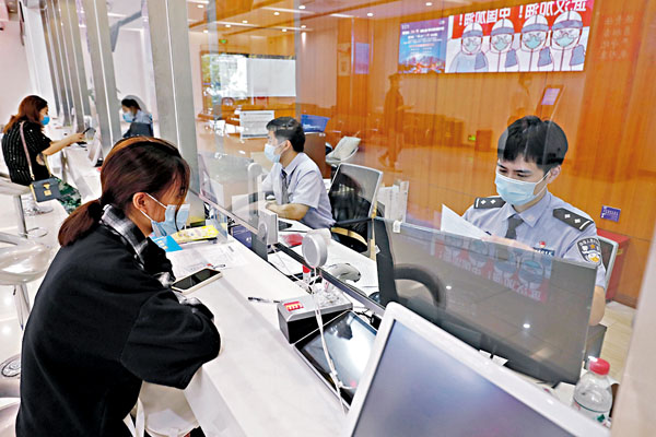 ■ 內地恢復辦理赴澳門旅遊簽註。圖為昨日在上海市公安局長寧分局出入境接待大廳，市民在窗口確認登記信息。 中新社