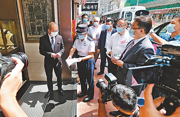 ■警方向金舖負責人派傳單，提醒要加強保安。香港文匯報記者  攝 