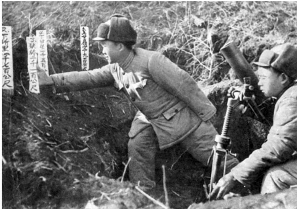 ■唐章洪（左前）正在把寫諸元參數的木牌往炮位上戳。 網上圖片