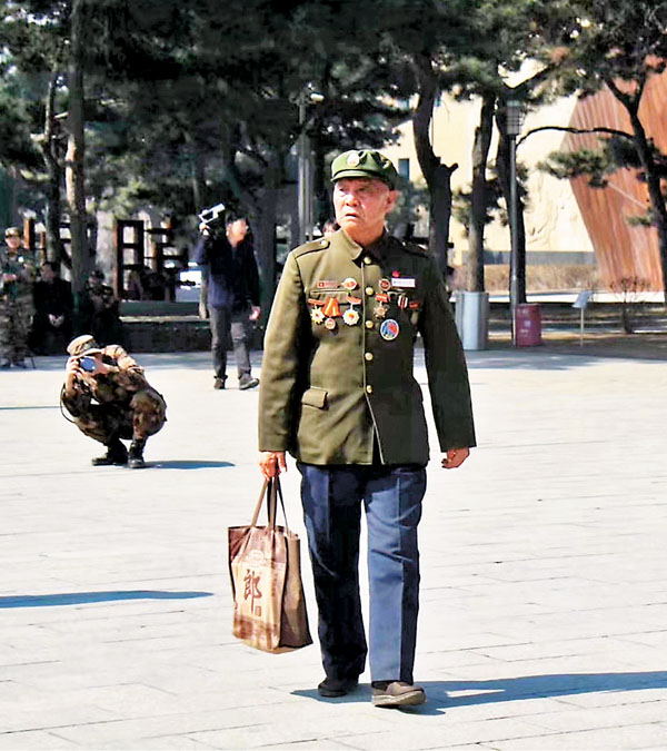 ■高磊（後）在抗美援朝烈士陵園為前來掃墓的老兵李維波拍照。 受訪者供圖
