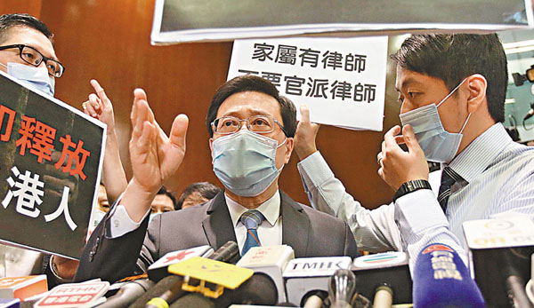 ■李家超（中）於立法會會議廳外見記者時，被攬炒派議員包圍阻撓。