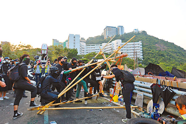 ■中大學生會幹事會臨時行政委員會及多個書院學生會近日籌辦所謂「歷史回顧活動」，乘機美化當日「佔校」暴徒為「義士」。圖為去年中大二橋上，黑衣魔用大型投擲器擲磚頭。 資料圖片