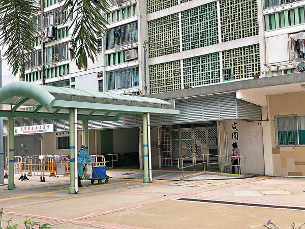 ■有身穿防護衣物的清潔工進出盛圍樓。 香港文匯報記者  攝