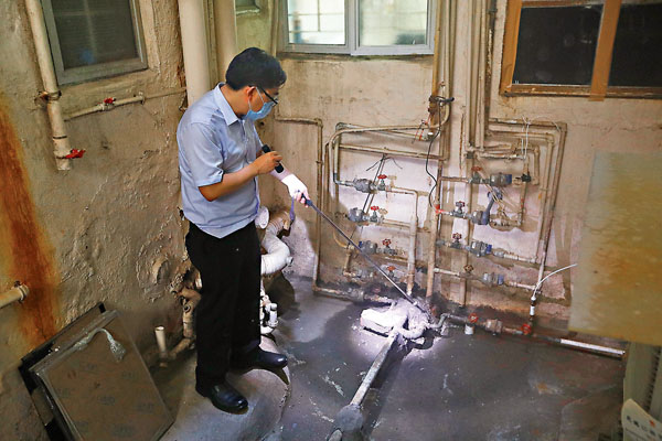■驗樓專家賴達明發現大廈供水喉地面接駁處潮濕，不排除供水喉漏水可能。香港文匯報記者  攝