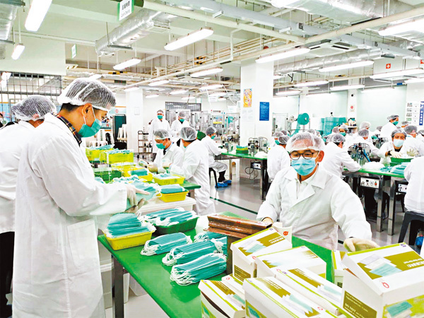 ●懲教署義工每天24小時趕製口罩，署長胡英明（右）連日落場做工人，將口罩包裝入盒。 懲教署提供