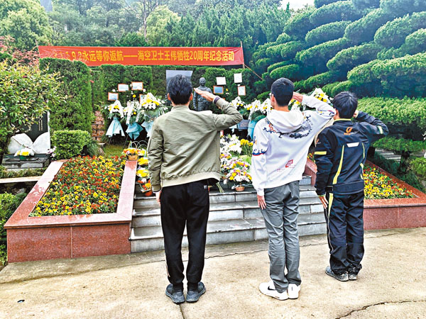 ● 三位前來祭掃的青年向英雄致敬。 香港文匯報記者俞晝  攝