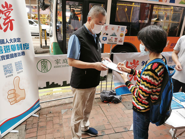 ● 施清流（左）街站呼籲市民簽名支持全國人大關於完善香港選舉制度的決定。