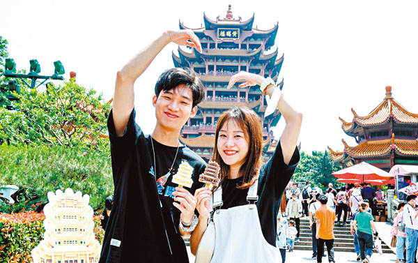 ●5月1日，來自廣州的遊客手拿黃鶴樓網紅雪糕在黃鶴樓前留影。 中通社