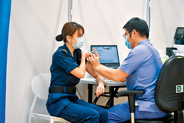 ●香港使用的復必泰和科興兩款疫苗的中和抗體水平都很理想。圖為一名海關人員（左）接種疫苗。 資料圖片