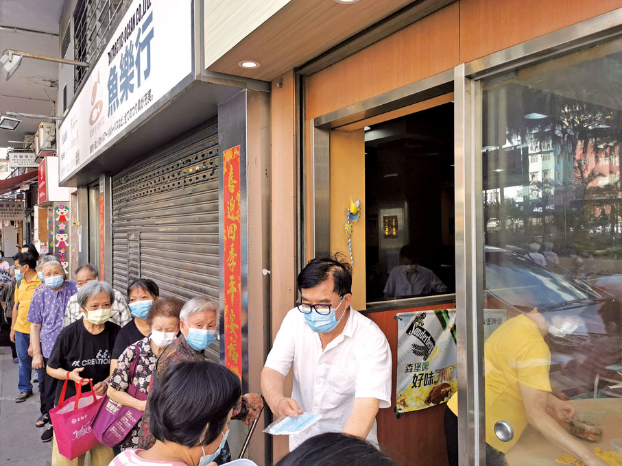 ● 何毅強為街坊免費派發口罩及飯盒。