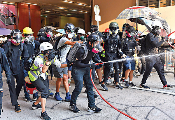 ●被告曾協助其他示威者用水喉噴向警方防線。圖為示威者向警方射水。 資料圖片