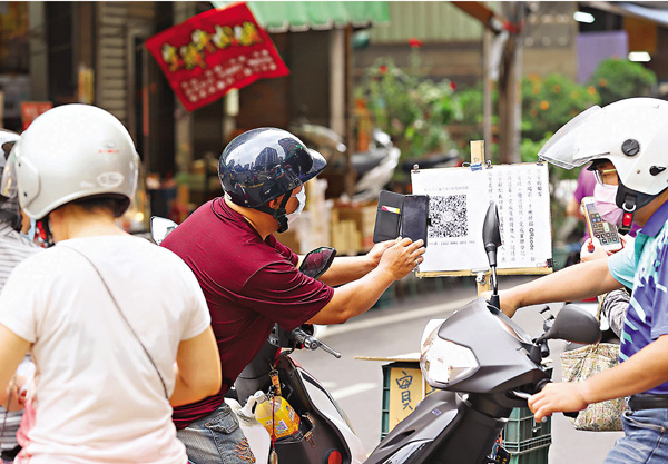 ●5月29日，台灣新北蘆洲菜市場在入口處量測民眾體溫，並進行實聯制，相關人員在一旁舉牌宣導防疫觀念。 中通社