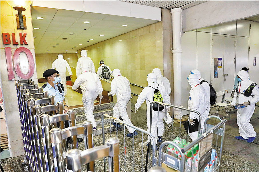 ●特區政府昨晚圍封確診女子居住的大埔中心第十座進行強制檢測，工作人員穿防護裝備進入第十座。 香港文匯報記者  攝