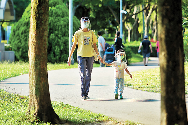 ●疫境下，不少島內職業媽媽表示工作及居家照顧孩子導致壓力過大。圖為早前台灣一名家長與孩子一起戴着口罩、面罩到戶外散步。資料圖片