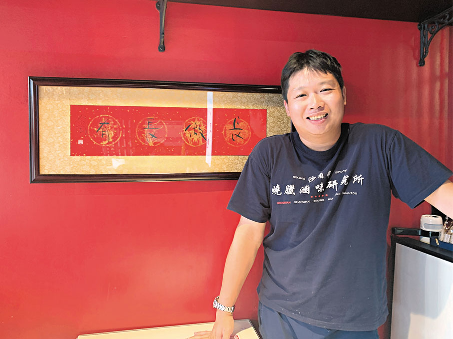 ●蔡志強在新店「燒臘滷味研究所」裏留影，身後是蔡瀾為其寫下的「長做長有」。 香港文匯報記者俞晝  攝