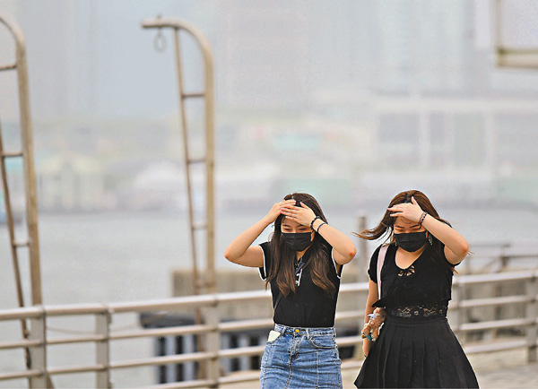 ●昨日一號戒備信號發出下，有市民行經尖沙咀海濱時遇上下雨，僅用手遮雨顯得十分狼狽。 中通社