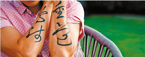 ● 麥秋成展示手上「尊師重道」紋身。