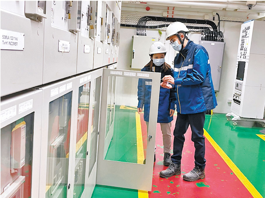 ●中華電力變電站建設經理譚銘僖（左二）為實習生時健寧（左一）解釋相關輸電系統零件。 香港文匯報記者  攝