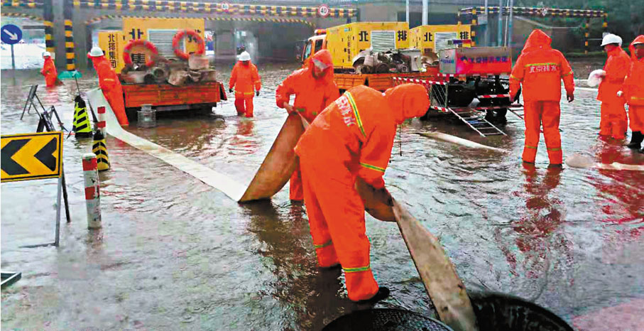 ●7月18日，暴雨襲擊了北京石景山區，北京排水集團的工作人員在一條積水的街道上排水。 新華社
