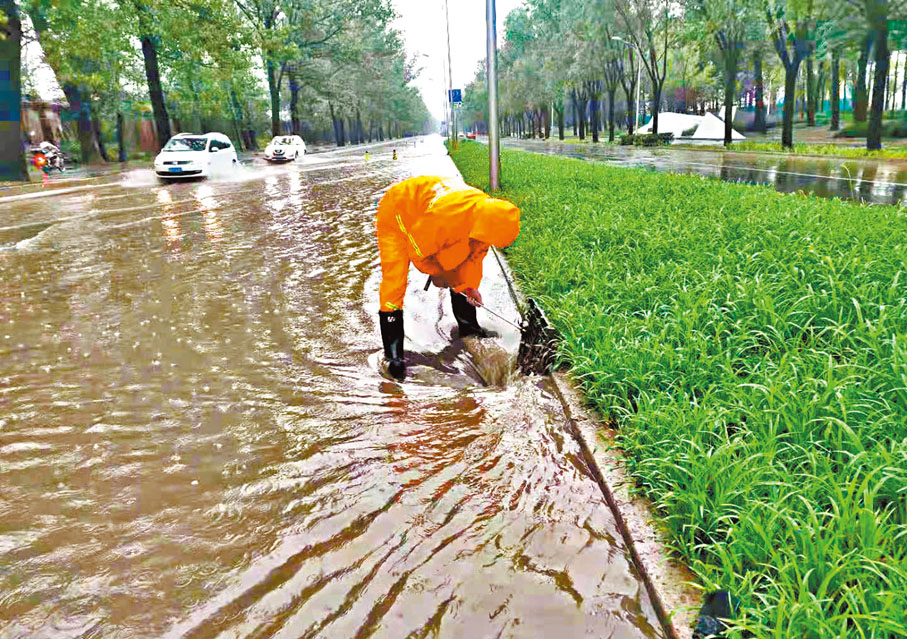 ●北京街頭積水嚴重，工作人員在清理下水道。 網上圖片