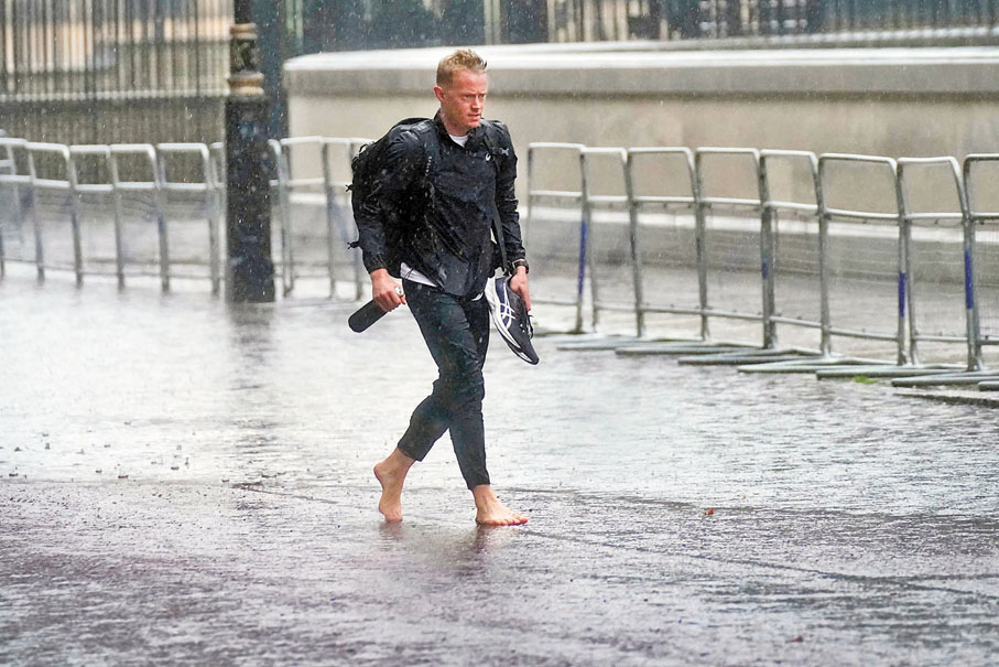 ● 面對大雨，有英國人索性除鞋上路。