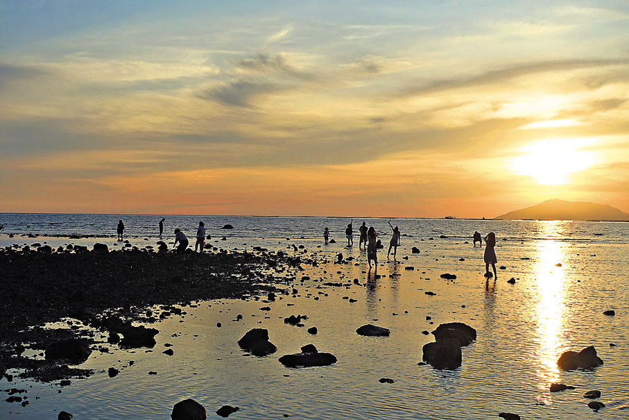 ●夕陽西下海邊「趕海」的遊客。 
