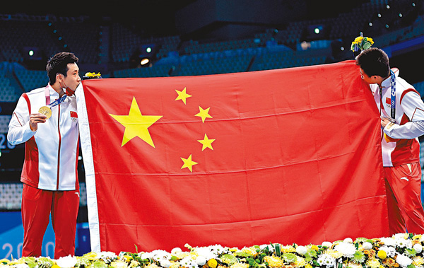 ●曹緣(左)與楊健在領獎牌後親吻國旗。  新華社