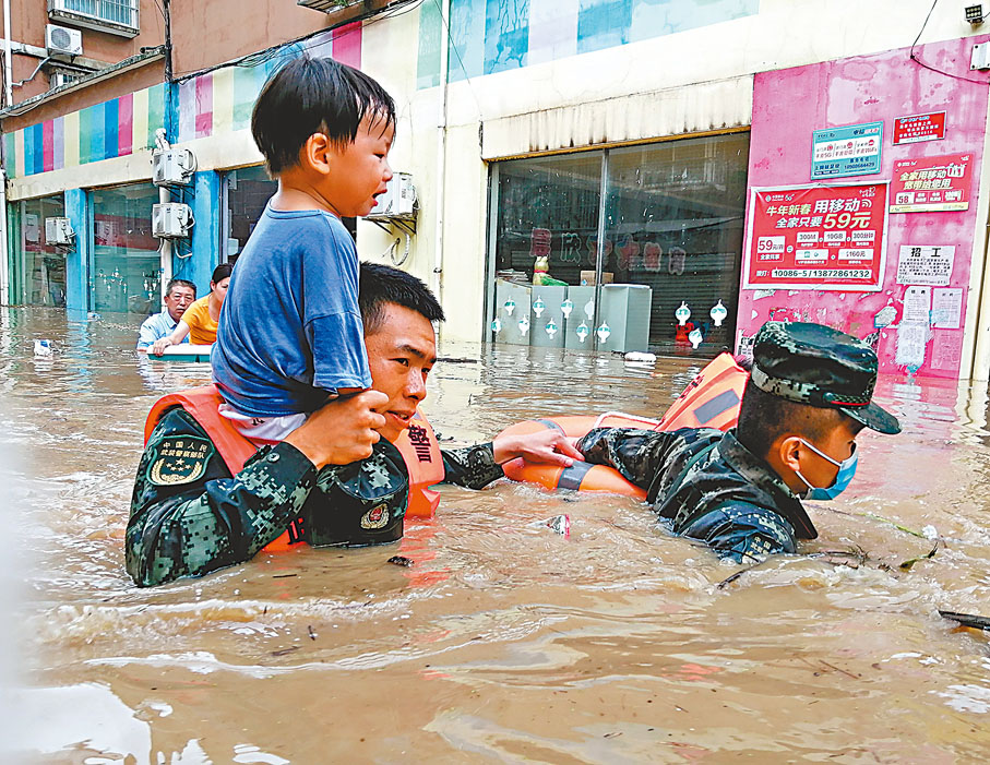 ●昨日，隨州市何店鎮，武警官兵將一名小朋友扛在肩上轉移到安全地帶。 中新社