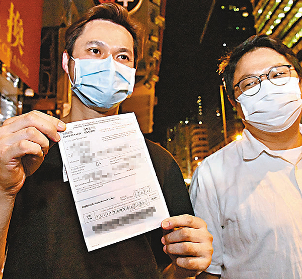 ●蕭德健（左）展示定額罰款通知書，右為朱江瑋。