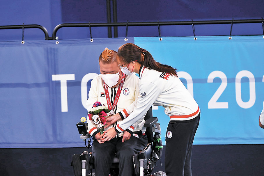 ●妻子施珊珊（右）親手為梁育榮掛上獎牌。香港殘奧會供圖