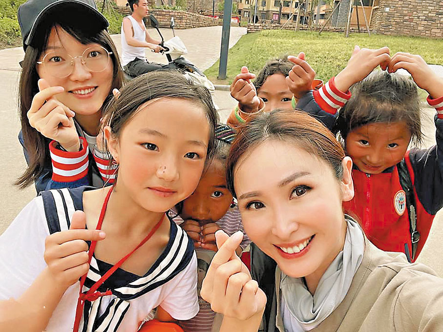 ●陳貝兒與彝族小朋友互傳愛心。