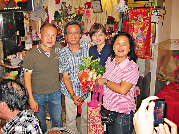 ●善信鍾先生（左）與手持花炮的「住持」葉金蘭（右）及其他善信合影。 受訪者供圖