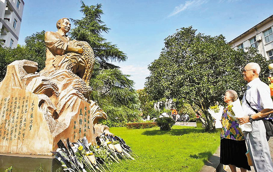●袁隆平同班同學陳德玖(右二)偕老伴到雕像前獻花。 網上圖片