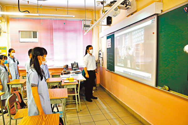 ●香港鮮魚行學校的師生在教室觀看旗手升旗。 新華社