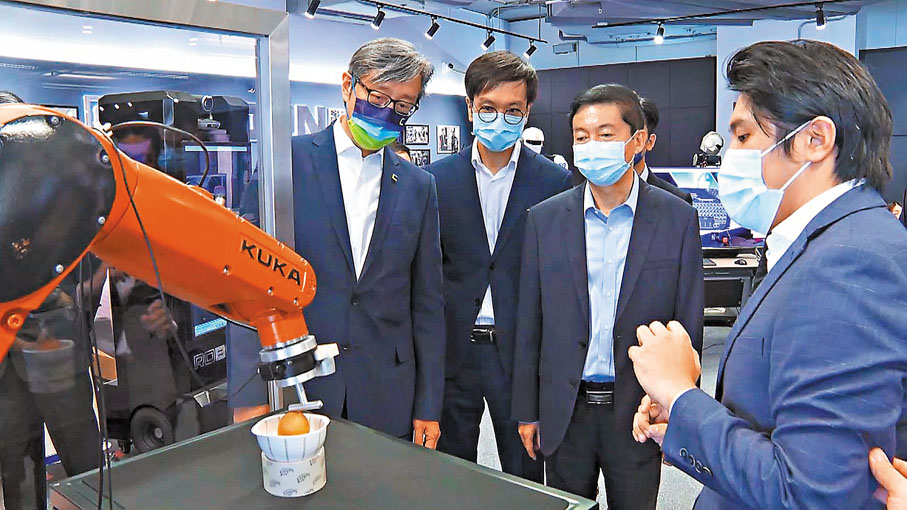 ●路邦科技公司(Roborn)聯合創始人麥騫譽（右一）向駱惠寧展示團隊最新研發的仿生機械人模型以及遙距操作機械人。 數碼港供圖