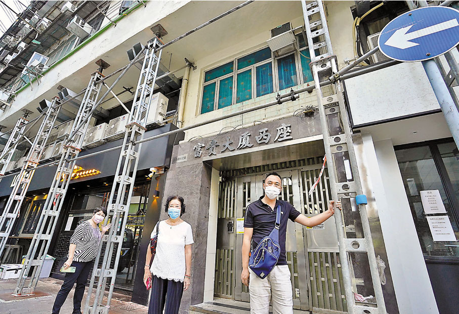 ●位於大角咀的富貴大廈分為東西兩幢，樓齡均逾60年，被屋宇署列為危樓，樓宇四周圍需用鐵架支撐。住戶廖太(左)和李女士(中)表示，支持政府調低舊樓強拍門檻。