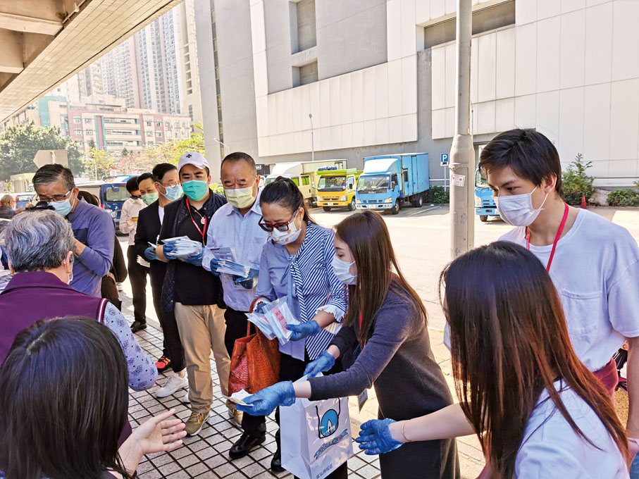 ● 余鵬春（右五）與愛心人士一起深入社區向市民派發口罩。