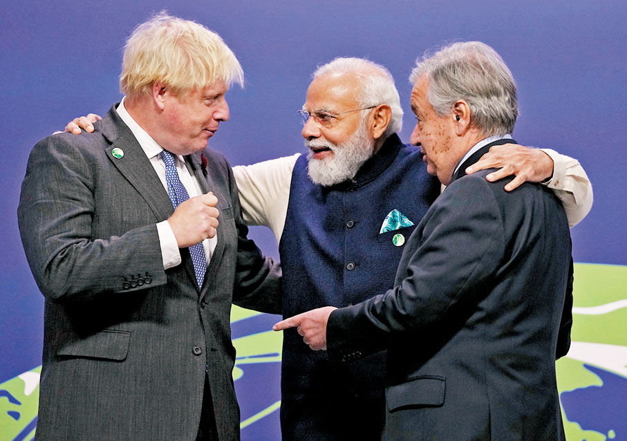● 印度總理莫迪（中）承諾2070年實現淨零排放。圖為他與英國首相約翰遜（左）及聯合國秘書長古特雷斯（右）密斟。 美聯社