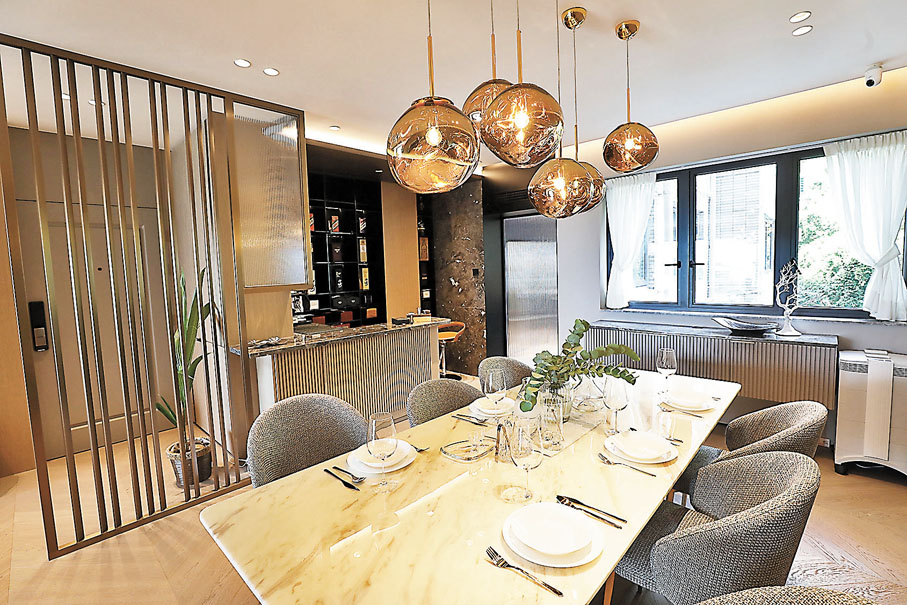 ●飯廳的特色吊燈與大理石長形飯桌，配上金屬物料和弧形條子牆身，營造出豪華的美感。