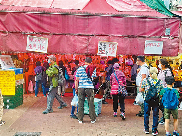 ●黃元興豬肉檔貼出告示稱要「同歸於盡、血戰到底」，不少市民在檔位前挑選，購買豬肉。 香港文匯報記者  攝