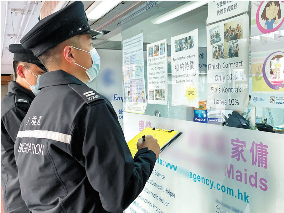 入境處職員於店外抄寫資料。