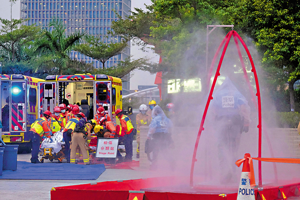 ●救護人員將模擬受化學襲擊污染者抬上救護車。 香港文匯報記者  攝