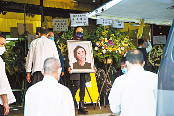 ●家屬捧着江迅的遺照步出紅磡世界殯儀館。 中新社