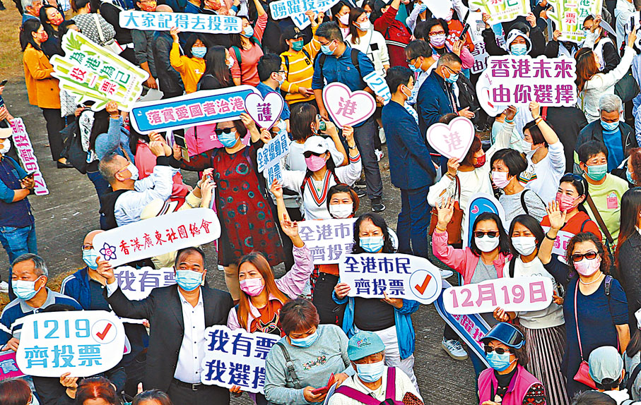 ●人們熱情高漲，手中揮動「為港為己投一票」等標語。香港文匯報記者  攝