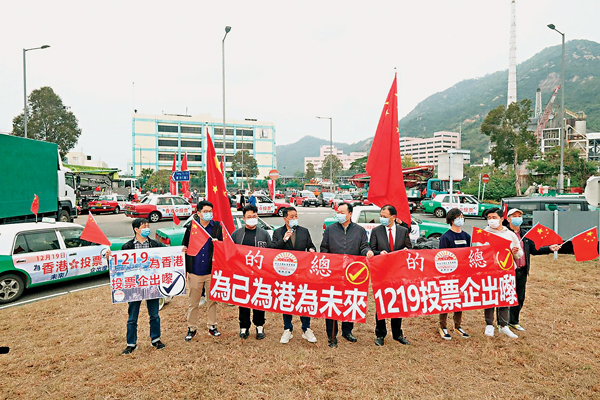●的士司機從業員總會會長林曉輝（左六）、理事長黃一峰（左四）及車隊長執委等高呼「為港為己為未來，1219投票企出嚟，支持『愛國者治港』」。 香港文匯報記者  攝