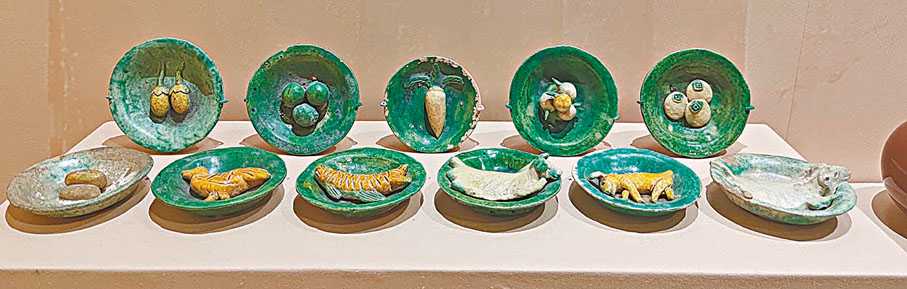 ◆明代供食具，山西晉城出土。此套供碟是專為墓主人燒製的隨葬品。十一個綠釉陶碟分別裝有雞、魚、蔬菜、水果以及糕點等食品。