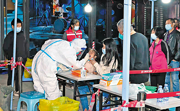 ◆廣中醫深圳醫院醫護人員在蓮花街道進行大型核酸檢測採樣時，彎腰給孩子進行核酸採樣。 香港文匯報記者郭若溪  攝