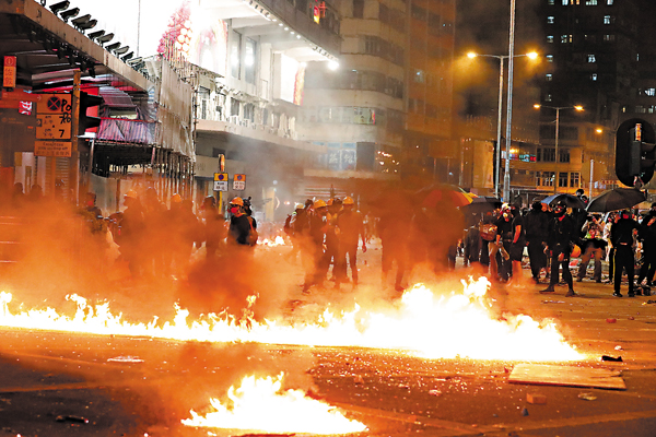 ◆2019年11月18日，大批黑暴分子為「營救」在理大校園內的暴徒，在油尖旺區打砸燒。被捕其中9人昨日被判刑。圖為當日暴徒在佐敦縱火。 資料圖片