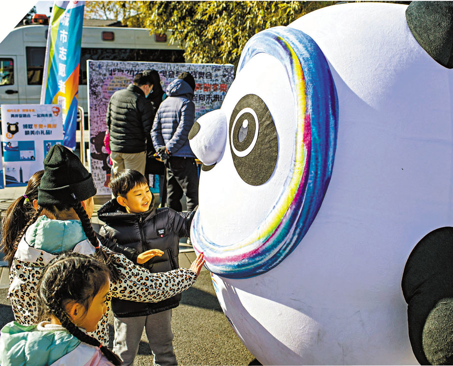 ◆小朋友們在北京市海淀區紫竹院街道的一處城市志願服務站與北京冬奧會吉祥物「冰墩墩」人偶互動玩耍。 中通社