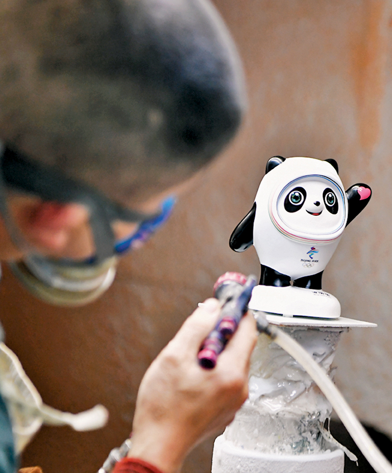 ◆工人為陶瓷「冰墩墩」噴上金油。